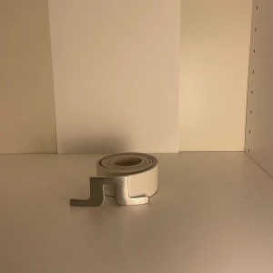 Vitt bälte från JLindeberg - Snyggt vitt bälte från JLindeberg med en unik metallspänne. Perfekt för att ge en stilren touch till din outfit. Bältet har en modern design och passar bra till jeans.