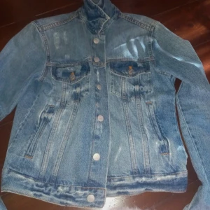 Blå jeansjacka - Snygg blå jeansjacka med knappar framtill och två bröstfickor. Perfekt för en avslappnad stil.
