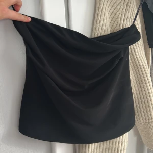 Svart tubtopp från Zara - Snygg svart tubtopp från Zara, perfekt för en stilren look. Tillverkad i ett mjukt och bekvämt material som sitter skönt mot huden. Passar utmärkt till både jeans och kjol. Ett måste i garderoben för alla modeälskare!