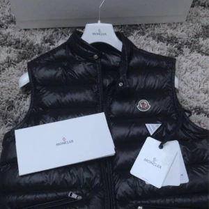 Svart dunväst från Moncler - Säljer en snygg och stilren svart Gui dunväst från Moncler köpt via Monclers hemsida. Västen är i storlek 3 (passar både S och M) och köpt för 9260kr. Västen är i nyskick utan några defekter eller skador. För frågor och annat är de bara att höra av sig. Pris kan diskuteras vid snabb affär. Obs inga byten! 