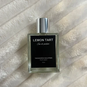 Lemon Tart Eau de Parfum - Gourmand och citruskakadoftande parfym i en elegant, fyrkantig glasflaska med en stilren svart etikett. Flaskan rymmer 50 ml och har en silverfärgad kork. Perfekt för dig som älskar gourmand och livliga dofter.