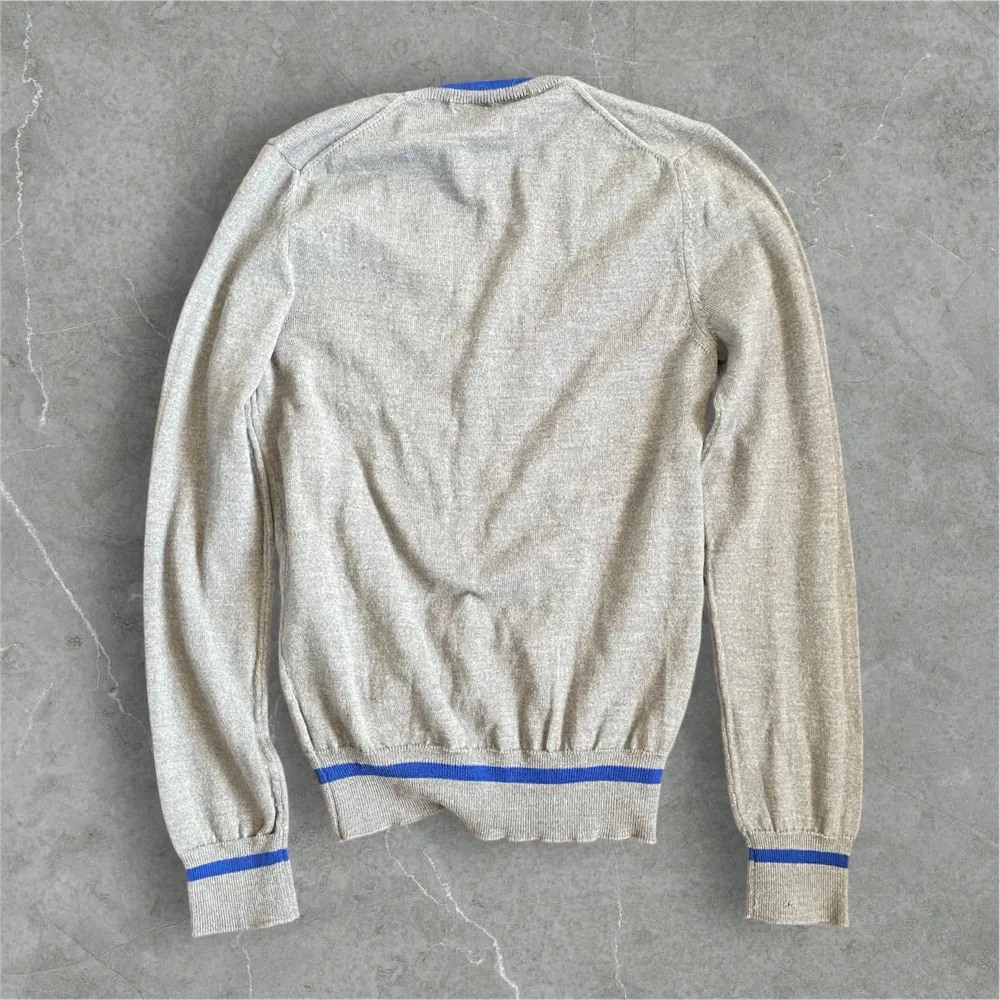 En stilren grå kofta från Comme des Garçons med blå detaljer. Defekt syns på sista bilden. Neuletakit & Villapaidat.