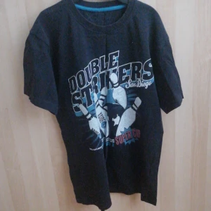 Svart t-shirt med tryck från XSide - Cool svart t-shirt från XSide med ett stort tryck på framsidan som säger 'Double Strikers San Diego'. Perfekt för en avslappnad stil. Kortärmad och bekväm passform.