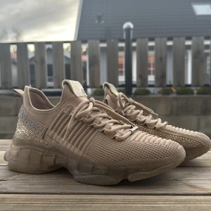 Beige sneakers med glittriga detaljer - Snygga beige sneakers med glittriga detaljer och snörning. Skorna har en stickad ovandel och en transparent sula som ger en modern look. Perfekta för att ge din outfit lite extra bling!
