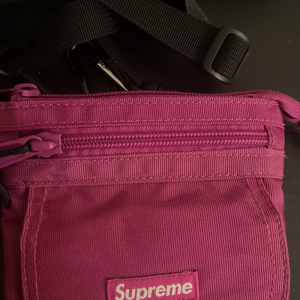 Säljer en snygg rosa axelväska från Supreme i slitstarkt Cordura-material. Väskan har en dragkedja upptill och en praktisk ficka framtill med Supreme-loggan. Perfekt för att bära med sig det viktigaste på språng.. Laukut & Käsilaukut.