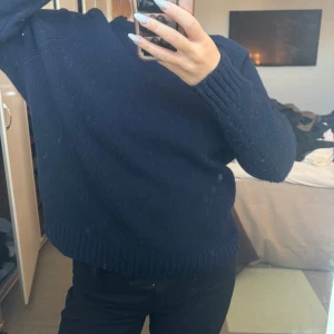 Mörkblå stickad tröja - Säljer en mysig mörkblå stickad tröja med långa ärmar och ribbstickade muddar. Perfekt för kyliga dagar. Passar bra till både jeans och kjol.
