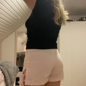 Rosa scandi shorts med rosetter - Säljer ett par söta ljusrosa shorts med dekorativa rosetter på sidorna. De har en dragkedja för enkel på- och avtagning. Perfekta för en somrig look!💕 står inte storlek men skulle säga ca M-L