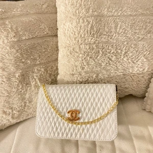 Vit quiltad handväska med guldkedja - Snygg vit quiltad handväska med en elegant guldkedja och ett stilrent märke framtill. Perfekt för att ge din outfit en lyxig touch. 👜✨