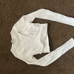 Vit croppad topp - Snygg vit topp med lång ärm och croppad passform. Perfekt för en trendig look med jeans eller kjol. Toppen har en stilren design som passar till många olika outfits.