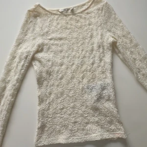 Vit långärmad topp från Aware - Säljer en stilren vit långärmad topp från Aware. Toppen har en unik textur och är perfekt för lager-på-lager eller att bära som den är. Passar bra till både jeans och kjol. Färgen är inte krut vit utan mer åt de kräm vita nästan beiga hållet skulle jag säga