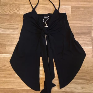 Svart knytlinne från Gina Tricot - Säljer ett somrigt svart linne från Gina Tricot med smala axelband och knytning framtill. Helt ny med lappar, jättesött linne som passar till mycket! Storlek xs men passar allt från xxs-s. Säljer eftersom jag inte behövder det💓 nypris 260kr
