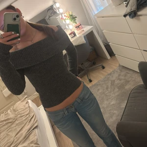 Grå offshoulder stickad tröja - Säljer en snygg grå stickad offshoulder-tröja. Tröjan har en tight passform och långa ärmar.