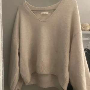 Beige stickad tröja med v-ringning - Mysig beige stickad tröja från H&M i storlek XS. Tröjan har en snygg v-ringad hals och ribbade muddar vid ärmslut o Passformen är loose och enkel att matcha. i fint skick 
