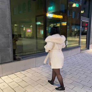 Beige kappa med pälsdetalj och bälte - Måste tyvärr säga hejdå till min fina beigea kappa som har en stor fluffig pälsdetalj vid kragen och bälte i midjan. Använd max 5 gånger så den ser helt ny ut. Den kommer aldrig till användning då jag gillar min svarta kappa mer. Passar alla storlekar då de är en one size. Jag har S/M och passar perfekt. 