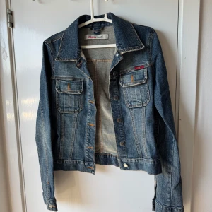 Blå jeansjacka från Only Jeans - Snygg klassisk blå jeansjacka från Only Jeans med coola kontrastsömmar och två bröstfickor med knapp. Jackan har krage, långa ärmar och knappar framtill. Perfekt för dig som vill ha en tidlös och chill look.