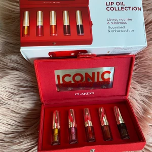 Clarins Lip Oil Anniversary Collection set - Snyggt set med fem ikoniska läppoljor från Clarins i en exlusiv lyxig röd väska som kommer med en silver axelramskedja och spegel. I sista bilden kan man se vilka läppoljor som ingår. Helt ny och oanvänd! Nypris: 445kr 