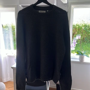 Mörkgrå stickad tröja från Strömberg - Säljer en mörkgrå stickad tröja från Strömberg i storlek L. Tröjan har rund hals, ribbade muddar vid ärmslut och nederkant samt långärmad passform. Perfekt för dig som gillar enkel och stilren design med lite loose fit.