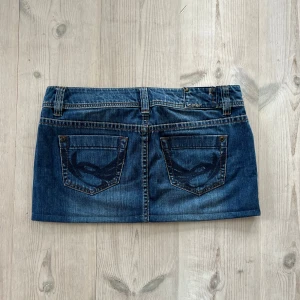 Blå lågmidjad jeanskjol  - Blå lågmidjad jeanskjol från Esprit i storlek 29, skulle säga att den passar som M. Tvärs över midjan är det 43 cm och den är 28 cm lång (längs med sidan). Fint skick. Använd gärna köp nu!