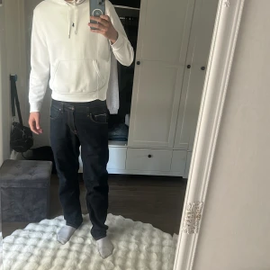 Vit hoodie från Polo Ralph Lauren - Säljer en fräsch vit hoodie från Polo Ralph Lauren med klassisk blå logga på bröstet. Hoodien har snörning vid huvan, stor magficka och mjukt bomullsmaterial. Perfekt för chill dagar och enkel att matcha med jeans eller joggers.