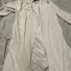 Beige trenchcoat med bälte - Snygg beige trenchcoat från Gina Tricot med klassisk krage och knytbart bälte i midjan. Jackan har långa ärmar och två fickor framtill. 