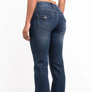 Låga bootcut jeans från Madlady i storlek 34 tall - Snygga blå bootcut jeans från Madlady i storlek EU34/Tall. Jeansen har låg midja, framfickor med dekorativa sömmar och bakfickor med lock och knappdetalj. Materialet är klassisk jeans med lätt tvättad look och markerade sömmar. Ordinarie pris är 700kr