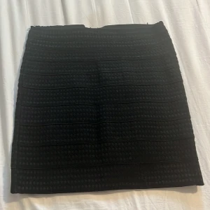 Svart kort kjol med strukturmönster - Snygg svart kort kjol med strukturerat mönster och markerade horisontella linjer. Kjolen har en rak passform och dragkedja baktill för enkel på- och avtagning. Perfekt för dig som gillar stilrena plagg med lite edge. Storlek M från Zara