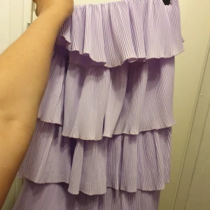 Ny ljuslila volangklänning från Boohoo - Superfin ny klänning från Boohoo i ljuslila med flera lager volanger och plisserat tyg. Klänningen har en flowy och luftig känsla💗 passar perfekt på mig som har M. Men inte min stil på kläder så säljer den vidare. Ny med prislapp på.
