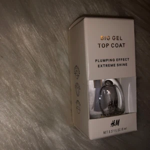 Big Gel Top Coat från H&M - Big Gel Top Coat från H&M med plumping-effekt och extrem glans. Kommer i en genomskinlig glasflaska med vit kork, 8 ml. Perfekt för att ge naglarna en snygg, glansig finish och extra volym.