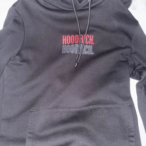Svart hoodie från Hoodrich med tryck - Svart hoodie från Hoodrich med stor logotyp i rött och grått på både bröstet och ryggen. Tröjan har huva med snörning och en stor magficka framtill. Materialet är mjuk bomull och passformen är normal. Perfekt för chill eller streetwear. Finns även matchade byxor aldrig använda, köp hela set för 500 eller hoddien 300 och byxan 200