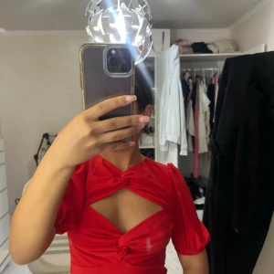 Röd omlottopp med puffärm från Gina Tricot - Säljer en röd omlottopp från Gina Tricot med puffärmar och knyt-detaljer framtill. 