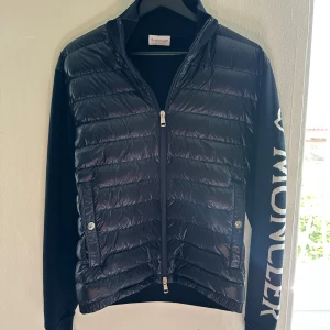 Moncler Cardigan - Snygg Cardigan från Moncler i en mörkblå färg, väldigt bra skick, knappt använd. I storlek S, nypris ca 6500kr. Köpt på MyTheresa, kvitto finns!
