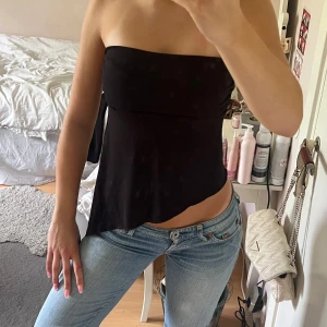 Asymmetrisk tubtopp  - Svart tubtopp från Urban Outfitters med  asymmetrisk/sne nederkant. Fint skick inga defekter. Använd fåtal gånger. Storlek S. 