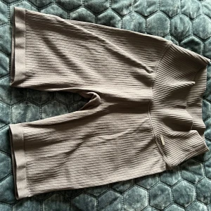 Ribbade beige shorts från Aimn - Snygga ribbade shorts från Aimn i gråaktig färg. De har hög midja och är tillverkade i ett stretchigt syntetmaterial med polyamid och elastan. Perfekta för träning eller chill dagar. Stilren design med bred linning och knälång passform. Använda endast ett fåtal gånger och i väldigt bra skick!