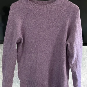 Ljuslila stickad tröja Vero Moda - Mysig ljuslila stickad tröja från Vero Moda i storlek S. Tröjan har rund hals, ribbade muddar och lång ärm. Perfekt för dig som gillar enkel och stilren design med mjukt material. Passar dig som vill ha en chill och comfy look.