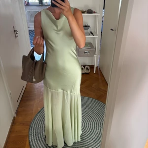 Ljusgrön långklänning från Mango - Helt ny med prislapp. Slutsåld på hemsidan, nypris 1049kr. Satin som övergår i brytande material nedanför höften. Tänkt att ha på bröllop men blev annan och returtiden gått ut. Piggelingrön. Jag är 164 och har på bilden 5 cm klack