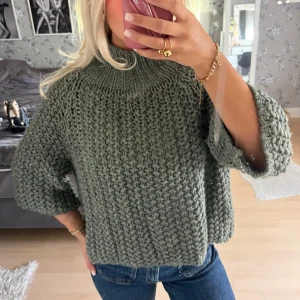 Olivgrön stickad tröja med hög krage - Säljer en chunky olivgrön stickad tröja med hög ribbad krage och trekvartsärmar. Tröjan har en loose och lite boxig passform, perfekt att slänga på över jeans. Grovstickad struktur som ger en cool och avslappnad vibe.