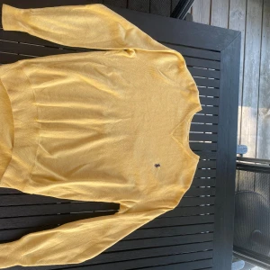 Gul bomullströja från Polo Ralph Lauren - Snygg gul tröja från Polo Ralph Lauren i 100% bomull. Klassisk rund hals och långärmad modell med den ikoniska Polo-loggan broderad på bröstet. Perfekt för dig som gillar stilrena och färgglada plagg. Passar dig som vill ha en normal passform. Original pris 1600kr