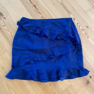 Blå volangkjol med snygga detaljer - Superfin vit kortkjol med flera volangdetaljer från Nelly. 