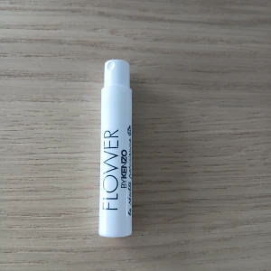 Flower by Kenzo parfymprov - Flower by Kenzo parfymprov i smidig vit sprayflaska. Minimalistisk design med svart text på cylindrisk plastflaska. Perfekt att ha med i väskan för en fräsch doftboost när som helst.