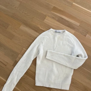 Vit stickad tröja från Zara - Mysig vit stickad tröja från Zara i storlek S. Tröjan har rund hals, långa ärmar och ribbade muddar vid nederkant och ärmslut. Perfekt för dig som gillar enkel och clean stil med en soft känsla. Passar dig som vill ha en basic men ändå snygg tröja.