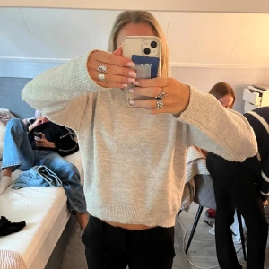 Beige stickad hoodie med huva - Mysig beige stickad hoodie med huva och snörning. Tröjan har långärmade ärmar och ribbade muddar vid ärmslut och nederkant. Perfekt för chill dagar och enkel att matcha med jeans eller mjukisbyxor.