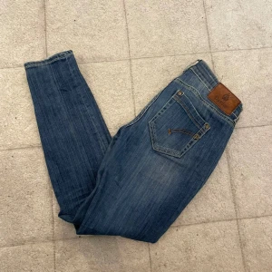 Dondup jeans  - Snygga blå jeans från dondup med klassisk femficksdesign och brunt läderpatch bak. Jeansen har skinny passform och smal siluett, med slitningar och tvättade detaljer som ger en cool look. Perfekt för dig som gillar stilrena och moderna jeans.