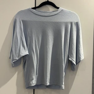 Ljusblå loose t-shirt från 157 - Ljusblå t-shirt från 157 i storlek XS. Modellen är loose fit med korta ärmar och rund halsringning. Materialet känns mjukt och lätt, perfekt för chill dagar. Enkel och stilren utan mönster eller detaljer, passar dig som gillar minimalistisk vibe.