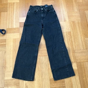 Svarta wide jeans från ONLY - Snygga svarta jeans från ONLY i modellen wide leg med hög midja. Klassisk femficksdesign och raka ben som ger en chill vibe. Tillverkade i slitstarkt denim med en mörk tvätt. Perfekta att matcha med sneakers eller boots för en cool look. De är uppsydda, passar någon på 150-165