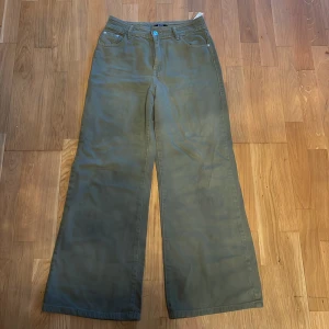 Olivgröna wide byxor med fickor - Snygga olivgröna byxor med breda ben och klassiska fickor både fram och bak. De har en normal midja och är tillverkade i ett mjukt bomullsmaterial som känns skönt mot huden. Perfekta för dig som gillar en avslappnad och trendig stil.