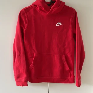 Röd hoodie från Nike - Säljer en röd hoodie från Nike med klassisk logga i vitt på bröstet. Tröjan har huva, magficka och lång ärm. Standard fit. 