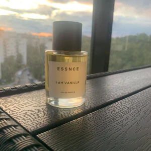 ESSNCE I Am Vanilla Eau de Parfum - Parfymflaska från ESSNCE med doften I Am Vanilla. Flaskan är cylindrisk i genomskinligt glas med ljusgul vätska och svart, matt kork. Minimalistisk etikett framtill. Perfekt för dig som gillar söta och varma vaniljtoner.