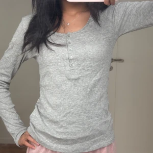 Grå ribbad långärmad topp - Jättesnygg ribbad topp från HM med knappar, knappt använd och passar jättebra med ett par jeans, och ännu bättre nu till hösten 🌻🌻🌻