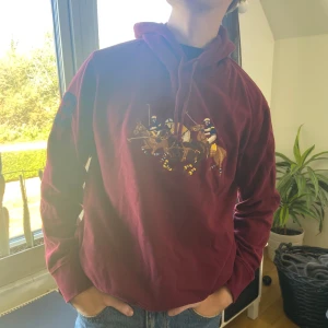 Polo Ralph Lauren vintage pullover hoodie - Vinröd vintage hoodie från Polo Ralph Lauren med deras signatur ”Triple-Pony” logga broderat på framsidan, i super fint skick, inga defekter