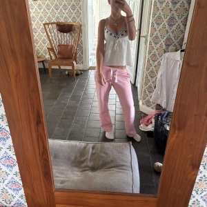 Vit linnetopp med blå broderi - Supersöt vit linnetopp med tunna axelband och blå broderade blommor vid bysten. Toppen har en lätt utsvängd passform och knyt under bysten för extra detalj. Perfekt för en chill och somrig vibe.